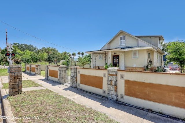 view of front of house with a fenced front yard, a gate, and stucco siding