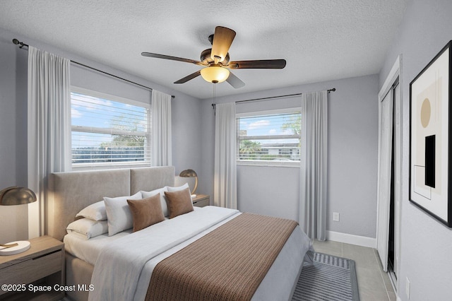 bedroom with light tile patterned floors, multiple windows, a ceiling fan, and a textured ceiling