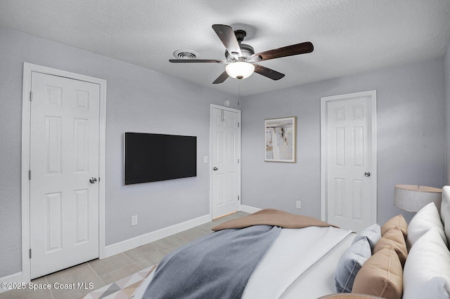 bedroom with visible vents, a textured ceiling, baseboards, and light tile patterned flooring