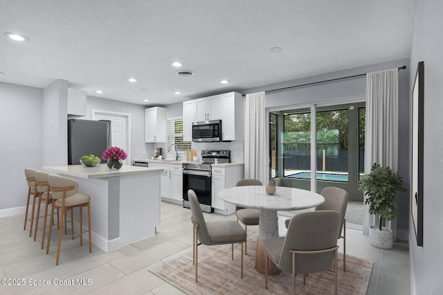 kitchen featuring visible vents, white cabinets, stainless steel appliances, light countertops, and a sink