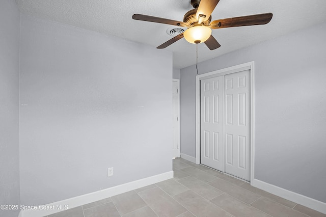 unfurnished bedroom with a textured ceiling, a closet, a ceiling fan, and baseboards