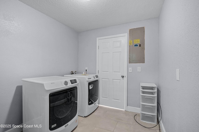 laundry area with laundry area, electric panel, washing machine and clothes dryer, a textured ceiling, and light tile patterned flooring