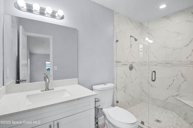 bathroom with toilet, a textured wall, vanity, and a marble finish shower