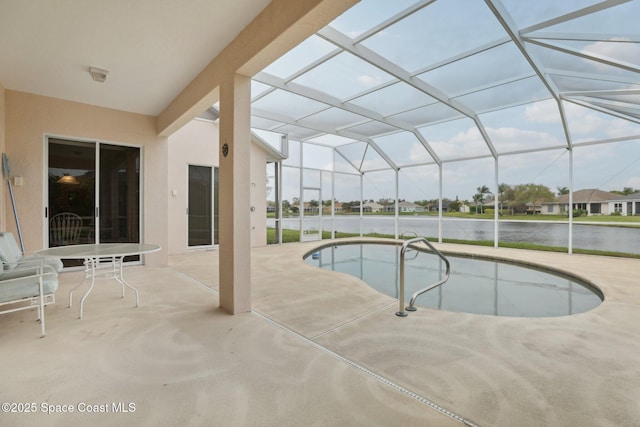 pool with glass enclosure, a patio area, and a water view