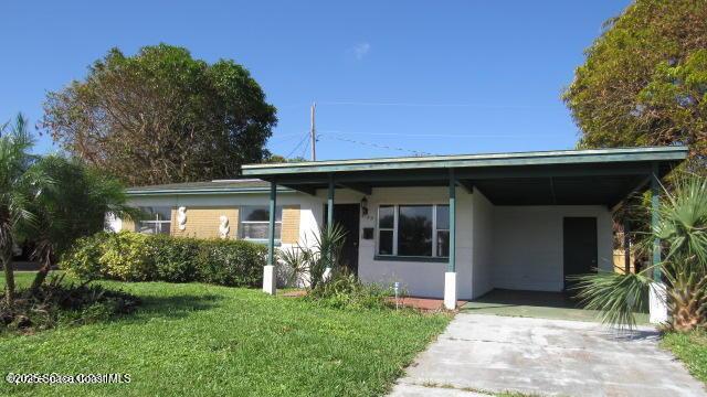 view of front of home with stucco siding, an attached carport, concrete driveway, and a front yard