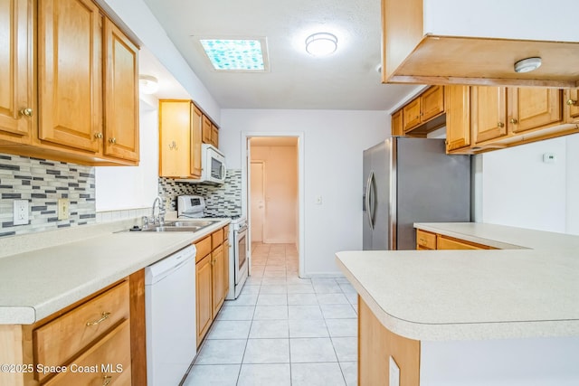 kitchen featuring white appliances, light tile patterned floors, backsplash, light countertops, and a sink