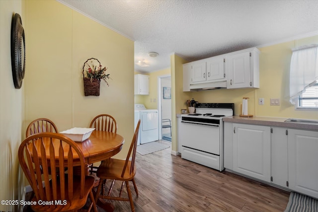 kitchen featuring under cabinet range hood, separate washer and dryer, wood finished floors, white cabinetry, and white range with electric cooktop