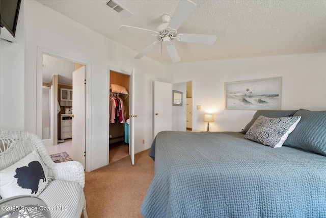 bedroom with a textured ceiling, a spacious closet, a closet, and light colored carpet