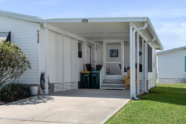 exterior space featuring entry steps, a carport, concrete driveway, and a front yard