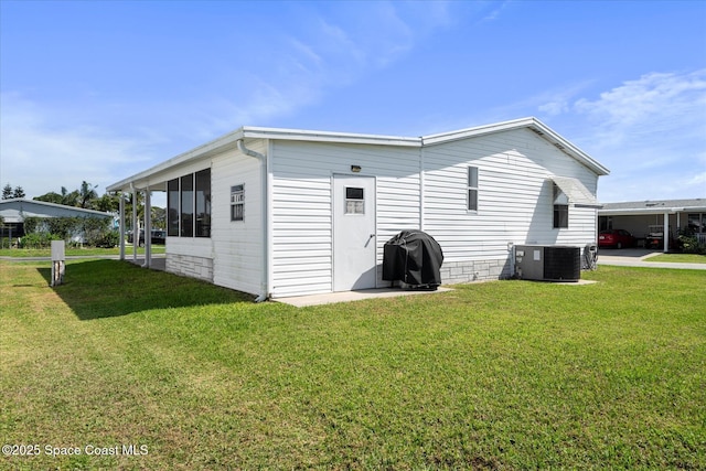 rear view of house with a carport, a lawn, cooling unit, and a sunroom