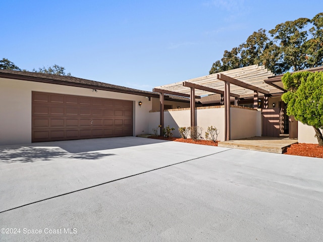 view of front facade featuring a garage, concrete driveway, a pergola, and stucco siding