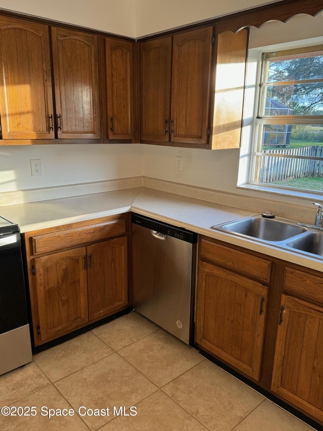 kitchen with light tile patterned flooring, stove, a sink, light countertops, and dishwasher