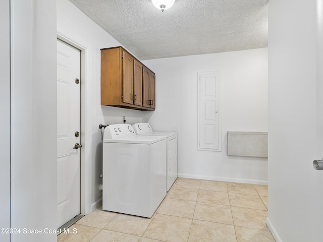 laundry area featuring light tile patterned floors, a textured ceiling, baseboards, cabinet space, and washer and clothes dryer