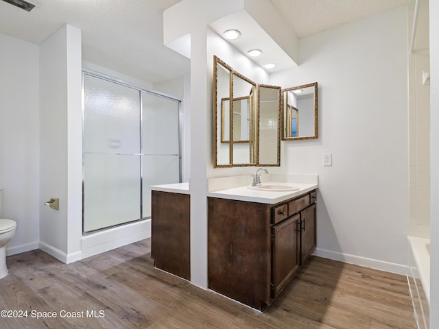 bathroom with toilet, a shower with door, wood finished floors, and vanity