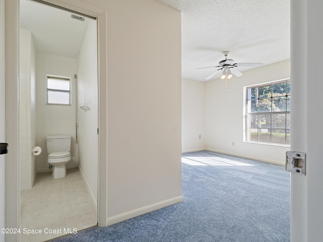 bathroom featuring a healthy amount of sunlight, baseboards, toilet, and a textured ceiling