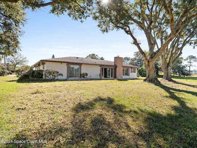 view of front of house with a front lawn, a chimney, and stucco siding