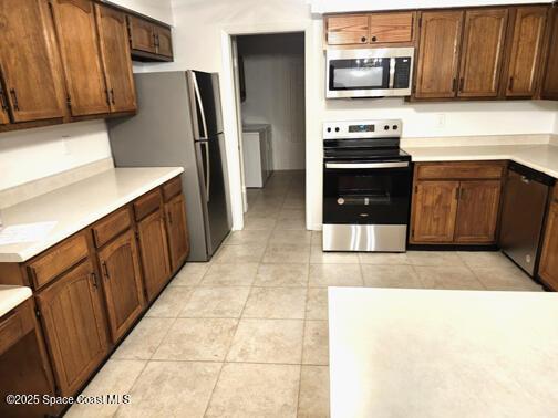 kitchen featuring stainless steel appliances, light countertops, and light tile patterned flooring