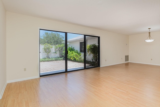 empty room with light wood-style floors, visible vents, and baseboards