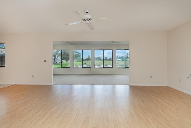 spare room with wood finished floors, a ceiling fan, and baseboards