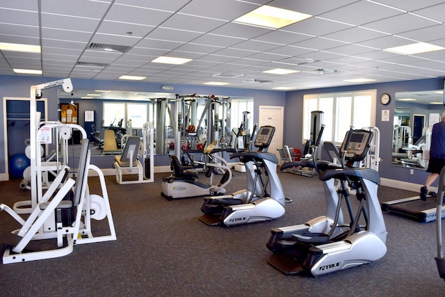 workout area with a drop ceiling, plenty of natural light, visible vents, and baseboards