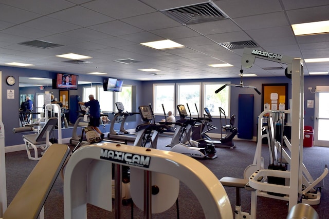 exercise room with baseboards, visible vents, and a drop ceiling