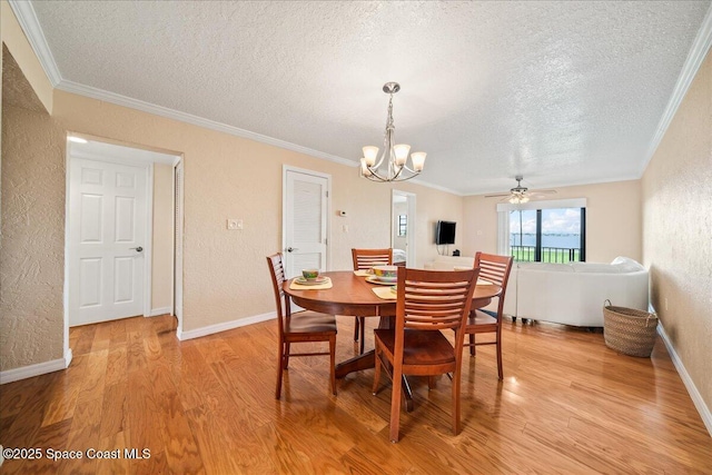 dining room with a textured wall, ornamental molding, and light wood-style flooring