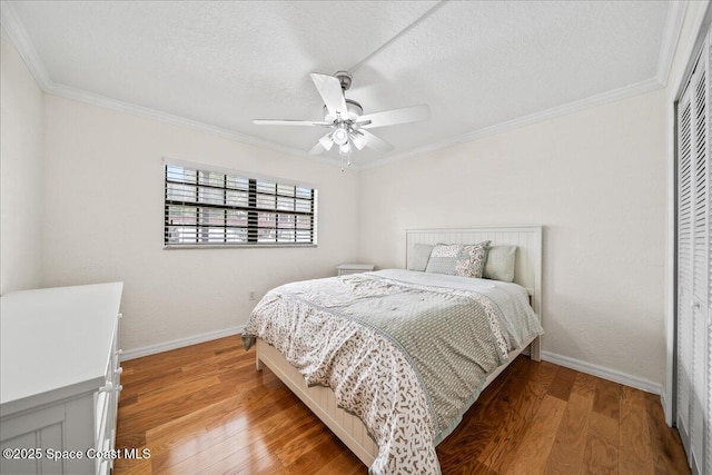 bedroom featuring crown molding, a closet, a textured ceiling, light wood-type flooring, and baseboards