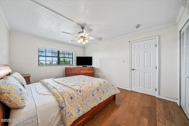 bedroom with a textured ceiling, ornamental molding, a closet, and wood finished floors