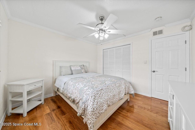 bedroom featuring light wood-style floors, crown molding, visible vents, and a closet