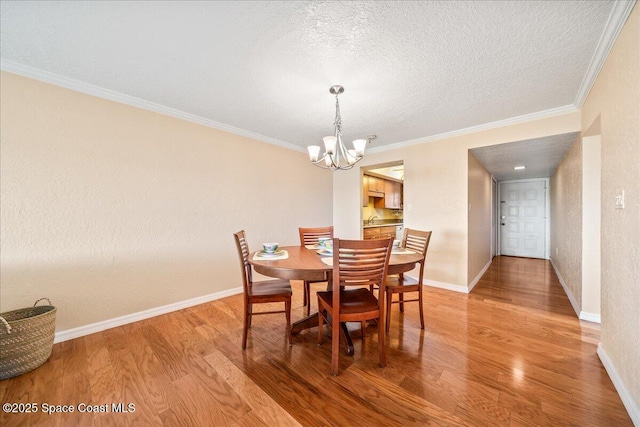 dining room with light wood-style floors, baseboards, a chandelier, and ornamental molding