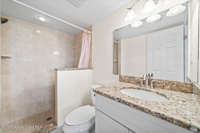 full bathroom featuring a textured ceiling, toilet, vanity, visible vents, and walk in shower