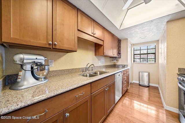 kitchen with dishwashing machine, a textured ceiling, brown cabinetry, and a sink