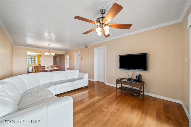 living area featuring a textured ceiling, ceiling fan with notable chandelier, baseboards, ornamental molding, and light wood finished floors