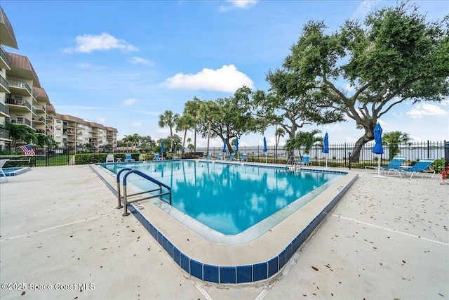 community pool with a patio area and fence