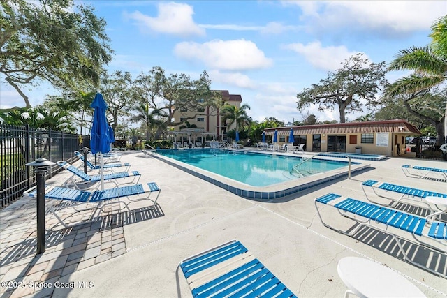 pool with a patio area and fence