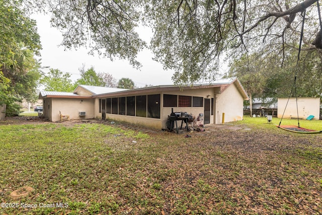 rear view of property with a lawn, a sunroom, metal roof, a shed, and an outdoor structure