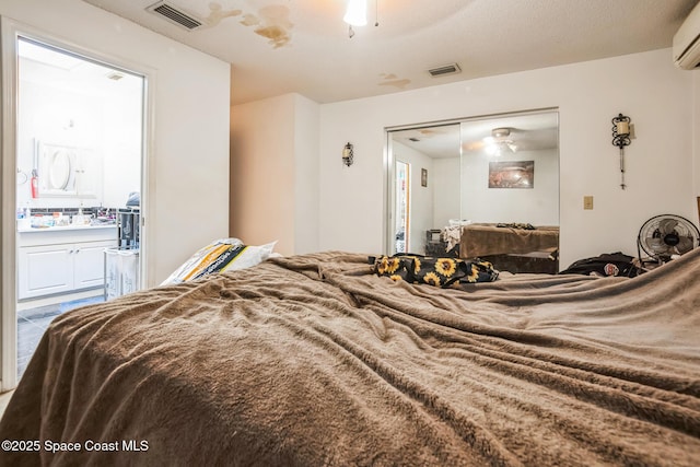 bedroom with an AC wall unit, a closet, ensuite bath, and visible vents