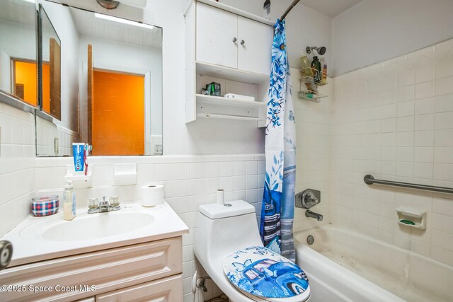 bathroom with toilet, tile walls, vanity, and shower / bath combo with shower curtain