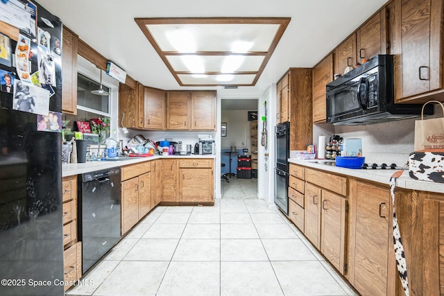 kitchen with light tile patterned floors, black appliances, and light countertops