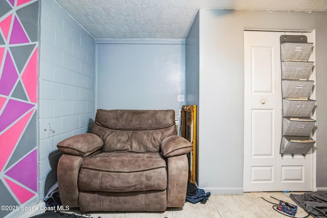 sitting room featuring concrete block wall and tile patterned floors