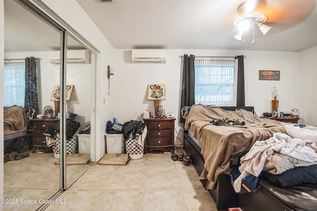 bedroom featuring a closet, a wall mounted air conditioner, a textured ceiling, and light tile patterned floors