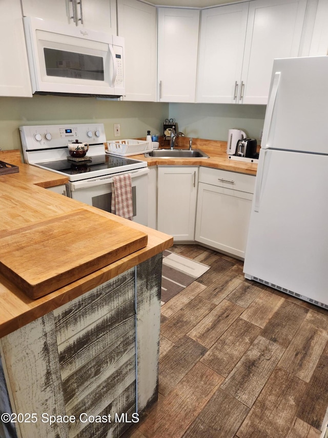 kitchen featuring white appliances, white cabinetry, wooden counters, and a sink