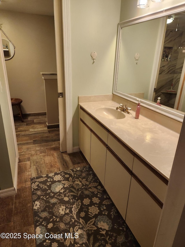 full bath featuring walk in shower, wood finished floors, vanity, and baseboards