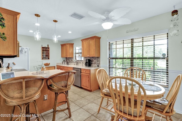 kitchen featuring a breakfast bar area, light countertops, backsplash, a sink, and dishwasher