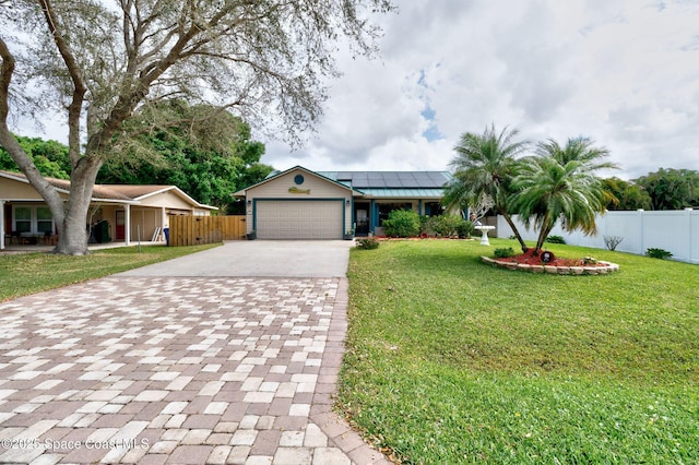 ranch-style house with a front yard, roof mounted solar panels, driveway, and fence