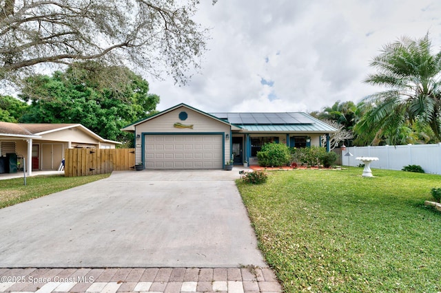 ranch-style house featuring a front yard, fence, driveway, and solar panels