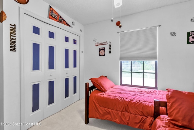 bedroom with a textured ceiling, a closet, and light colored carpet