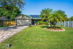 view of front of home featuring an attached garage, fence, concrete driveway, roof mounted solar panels, and a front yard