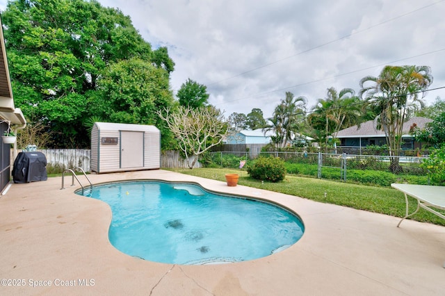 view of swimming pool with an outbuilding, a patio area, a fenced backyard, and a storage unit