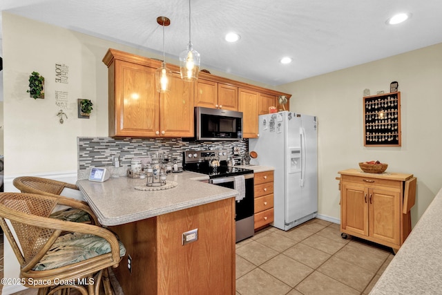 kitchen with a breakfast bar area, a peninsula, light countertops, appliances with stainless steel finishes, and tasteful backsplash